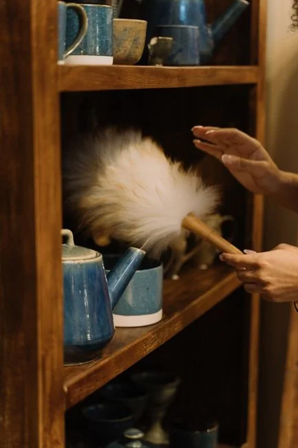 Anonymous male in yellow rubber gloves wiping foam from round mirror in bathroom
